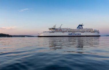 Victoria, Vancouver Island, British Columbia, Canada - July 13, 2022: BC Ferries Boat leaving the Terminal in Swartz Bay during colorful summer sunset.