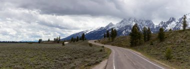 Scenic Road surrounded by Mountains in American Landscape. Spring Season. Grand Teton National Park. Wyoming, United States. Nature Background Panorama