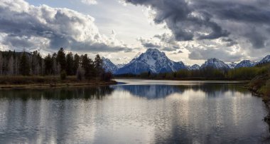 River surrounded by Trees and Mountains in American Landscape. Snake River, Oxbow Bend. Spring Season. Grand Teton National Park. Wyoming, United States. Nature Background Panorama. Sunset