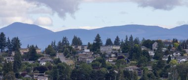 Homes by the water, surrounded by tees and mountains. Summer Season. Nanaimo, Vancouver Island, British Columbia, Canada. City Background.