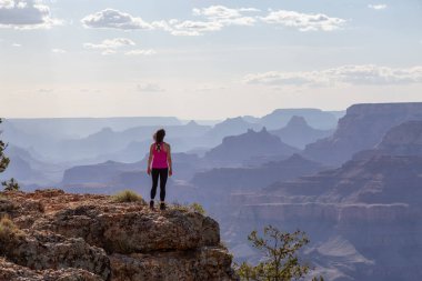 Adventurous Traveler standing on Desert Rocky Mountain American Landscape. Cloudy Sunny Sky. Grand Canyon National Park, Arizona, United States. Adventure Travel