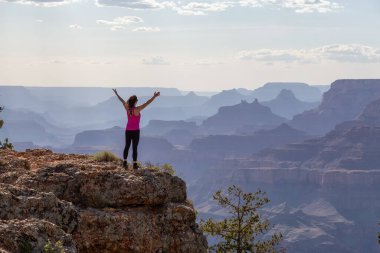 Adventurous Traveler standing on Desert Rocky Mountain American Landscape. Cloudy Sunny Sky. Grand Canyon National Park, Arizona, United States. Adventure Travel