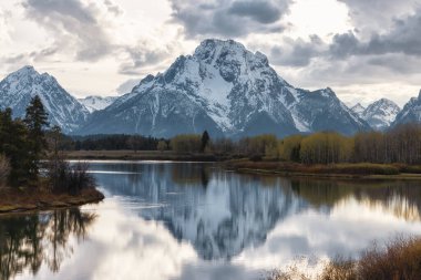 River surrounded by Trees and Mountains in American Landscape. Snake River, Oxbow Bend. Spring Season Sunset. Grand Teton National Park. Wyoming, United States. Nature Background.