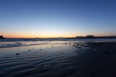 Sandy Beach on the West Coast of Pacific Ocean. Canadian Nature Landscape Background. Sunny Sunset Twilight. Cox Bay, Tofino, Vancouver Island, BC, Canada.