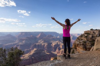 Adventurous Traveler standing on Desert Rocky Mountain American Landscape. Cloudy Sunny Sky. Grand Canyon National Park, Arizona, United States. Adventure Travel