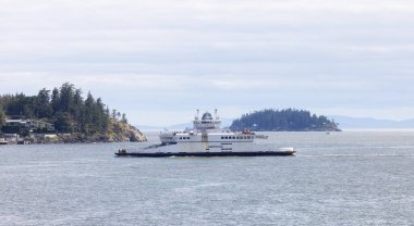 West Vancouver, British Columbia, Canada - July 10, 2022: BC Ferries Boat in Howe Sound with Islands and Canadian Mountain Landscape in Background.