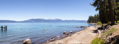 Panoramic View of Rocky Beach and Dock at the Lake surrounded by Mountains and Trees. Summer Season. Sugar Pine Point Beach, Tahoma, California, United States. Sugar Pine Point State Park. Panorama