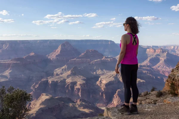 Adventurous Traveler standing on Desert Rocky Mountain American Landscape. Cloudy Sunny Sky. Grand Canyon National Park, Arizona, United States. Adventure Travel