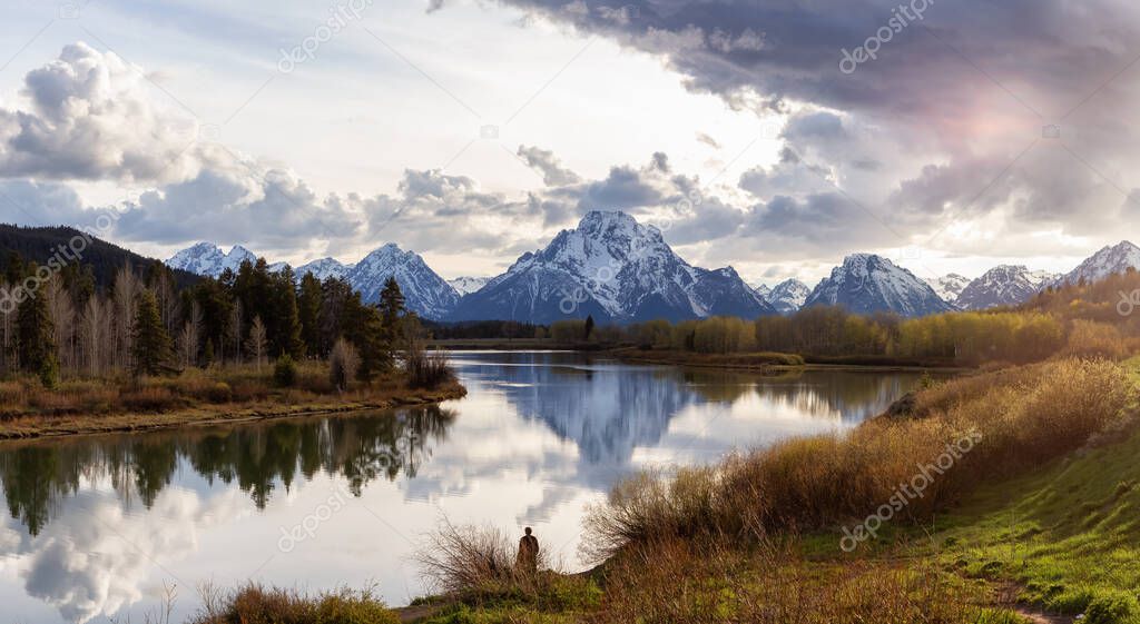 River surrounded by Trees and Mountains in American Landscape. Snake River, Oxbow Bend. Spring Season. Grand Teton National Park. Wyoming, United States. Nature Background Panorama. Sunset Cloudy Sky
