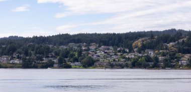 Homes by the water, surrounded by tees and mountains. Summer Season. Nanaimo, Vancouver Island, British Columbia, Canada. City Background.