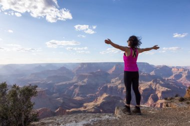 Adventurous Traveler standing on Desert Rocky Mountain American Landscape. Cloudy Sunny Sky. Grand Canyon National Park, Arizona, United States. Adventure Travel