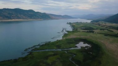 Aerial View of Okanagan Lake with farm lands and mountain landscape. Cloudy Sunset Sky. Near Vernon, British Columbia, Canada.