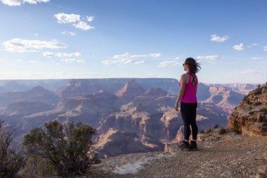 Adventurous Traveler standing on Desert Rocky Mountain American Landscape. Cloudy Sunny Sky. Grand Canyon National Park, Arizona, United States. Adventure Travel