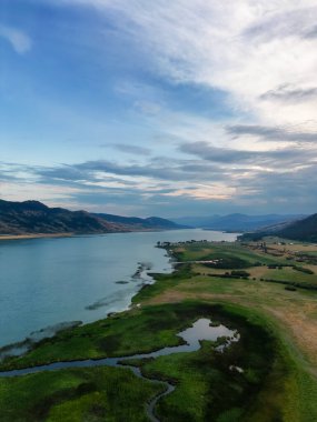 Aerial View of Okanagan Lake with farm lands and mountain landscape. Cloudy Sunset Sky. Near Vernon, British Columbia, Canada.