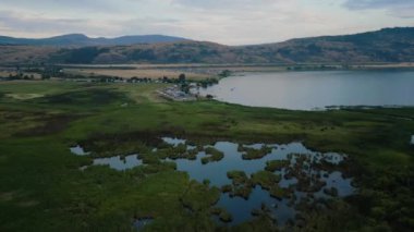 Aerial View of Okanagan Lake with farm lands and mountain landscape. Cloudy Sunset Sky. Near Vernon, British Columbia, Canada.