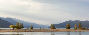 Sandy Beach on the lake with Canadian Mountain Landscape in background. Summer Sunset. Harrison Hot Springs, British Columbia, Canada.