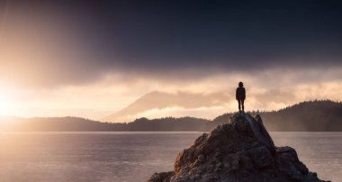 Adventurous Woman Hiking on the Rocky Coast with Mountains and Dramatic Sunset Sky. Adventure Composite. 3d Rendering Rocks. Background from West Coast of British Columbia, Canada.