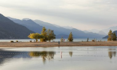 Sandy Beach on the lake with Canadian Mountain Landscape in background. Summer Sunset. Harrison Hot Springs, British Columbia, Canada.