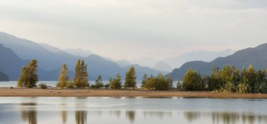 Sandy Beach on the lake with Canadian Mountain Landscape in background. Summer Sunset. Harrison Hot Springs, British Columbia, Canada.
