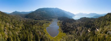 Aerial View of Green Canadian Nature Landscape. Lake around Mountains. Sunny Summer Day. Near Harrison Hot Springs, British Columbia, Canada. Panorama Background