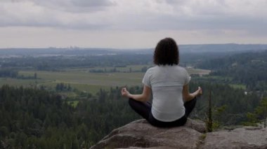 Adventurous Woman in Meditation overlooking the Canadian Nature Landscape. Minnekhada Regional Park, Coquitlam, Vancouver, British Columbia, Canada.