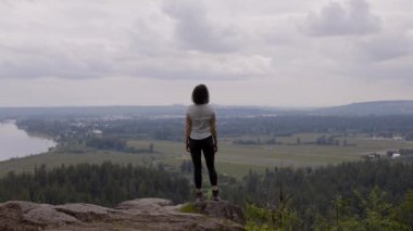 Adventurous Woman Standing on top of a rock overlooking the Canadian Nature Landscape. Minnekhada Regional Park, Coquitlam, Vancouver, British Columbia, Canada.