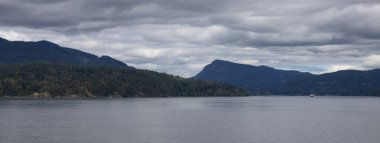 Treed Island with Homes and ferry passing by, surrounded by ocean and mountains. Summer Season. Gulf Islands near Vancouver Island, British Columbia, Canada. Canadian Landscape.