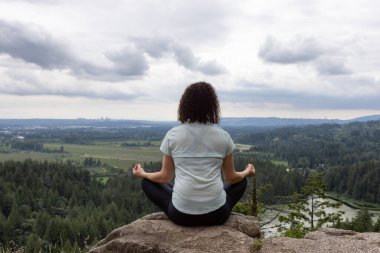 Adventurous Woman in Meditation overlooking the Canadian Nature Landscape. Minnekhada Regional Park, Coquitlam, Vancouver, British Columbia, Canada.