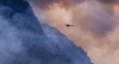 Sıcak bir yaz günü, Hope yakınlarındaki dağda, BC Orman Yangını ve Dumanı 'nın üzerinde uçan Wildfire Servis Helikopteri. British Columbia, Kanada. Doğal Felaket