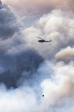 Sıcak bir yaz günü, Hope yakınlarındaki dağda, BC Orman Yangını ve Dumanı 'nın üzerinde uçan Wildfire Servis Helikopteri. British Columbia, Kanada. Doğal Felaket