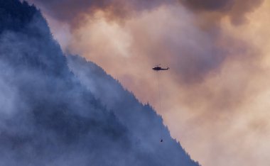 Sıcak bir yaz günü, Hope yakınlarındaki dağda, BC Orman Yangını ve Dumanı 'nın üzerinde uçan Wildfire Servis Helikopteri. British Columbia, Kanada. Doğal Felaket