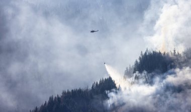 Sıcak bir yaz günü, Hope yakınlarındaki dağda, BC Orman Yangını ve Dumanı 'nın üzerinde uçan Wildfire Servis Helikopteri. British Columbia, Kanada. Doğal Felaket