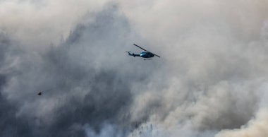 Sıcak bir yaz günü, Hope yakınlarındaki dağda, BC Orman Yangını ve Dumanı 'nın üzerinde uçan Wildfire Servis Helikopteri. British Columbia, Kanada. Doğal Felaket