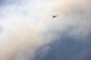 Sıcak bir yaz günü, Hope yakınlarındaki dağda, BC Orman Yangını ve Dumanı 'nın üzerinde uçan Wildfire Servis Helikopteri. British Columbia, Kanada. Doğal Felaket