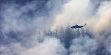 Sıcak bir yaz günü, Hope yakınlarındaki dağda, BC Orman Yangını ve Dumanı 'nın üzerinde uçan Wildfire Servis Helikopteri. British Columbia, Kanada. Doğal Felaket