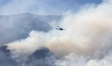 Sıcak bir yaz günü, Hope yakınlarındaki dağda, BC Orman Yangını ve Dumanı 'nın üzerinde uçan Wildfire Servis Helikopteri. British Columbia, Kanada. Doğal Felaket