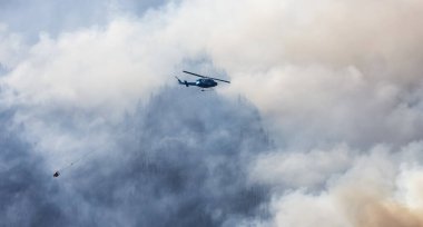 Sıcak bir yaz günü, Hope yakınlarındaki dağda, BC Orman Yangını ve Dumanı 'nın üzerinde uçan Wildfire Servis Helikopteri. British Columbia, Kanada. Doğal Felaket