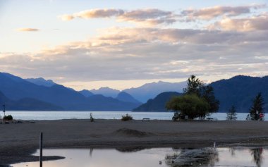 Kanada Dağ manzaralı göl kıyısında küçük bir turistik kasaba. Güneşli Yaz Günbatımı Gökyüzü. Harrison Kaplıcaları, British Columbia, Kanada.