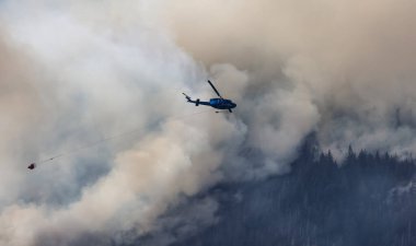 Sıcak bir yaz günü, Hope yakınlarındaki dağda, BC Orman Yangını ve Dumanı 'nın üzerinde uçan Wildfire Servis Helikopteri. British Columbia, Kanada. Doğal Felaket