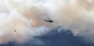 Sıcak bir yaz günü, Hope yakınlarındaki dağda, BC Orman Yangını ve Dumanı 'nın üzerinde uçan Wildfire Servis Helikopteri. British Columbia, Kanada. Doğal Felaket