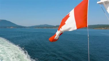 Kanada Ulusal Bayrağı Vancouver Adası, British Columbia, Kanada yakınlarında seyahat eden bir geminin arkasında. Macera Yolculuğu Konsepti. Yavaş Hareket