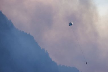 Sıcak bir yaz günü, Hope yakınlarındaki dağda, BC Orman Yangını ve Dumanı 'nın üzerinde uçan Wildfire Servis Helikopteri. British Columbia, Kanada. Doğal Felaket