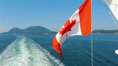 Kanada Ulusal Bayrağı Vancouver Adası, British Columbia, Kanada yakınlarında seyahat eden bir geminin arkasında. Macera Yolculuğu Konsepti. Yavaş Hareket