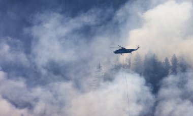 Sıcak bir yaz günü, Hope yakınlarındaki dağda, BC Orman Yangını ve Dumanı 'nın üzerinde uçan Wildfire Servis Helikopteri. British Columbia, Kanada. Doğal Felaket