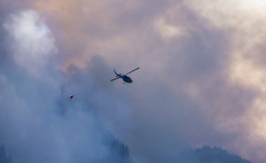 Sıcak bir yaz günü, Hope yakınlarındaki dağda, BC Orman Yangını ve Dumanı 'nın üzerinde uçan Wildfire Servis Helikopteri. British Columbia, Kanada. Doğal Felaket
