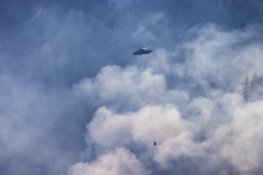 Sıcak bir yaz günü, Hope yakınlarındaki dağda, BC Orman Yangını ve Dumanı 'nın üzerinde uçan Wildfire Servis Helikopteri. British Columbia, Kanada. Doğal Felaket