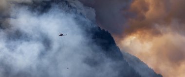 Sıcak bir yaz günü, Hope yakınlarındaki dağda, BC Orman Yangını ve Dumanı 'nın üzerinde uçan Wildfire Servis Helikopteri. British Columbia, Kanada. Doğal Felaket