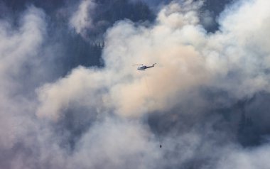 Sıcak bir yaz günü, Hope yakınlarındaki dağda, BC Orman Yangını ve Dumanı 'nın üzerinde uçan Wildfire Servis Helikopteri. British Columbia, Kanada. Doğal Felaket