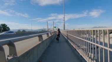 Bisiklet kullanan bir kadın, Fraser nehri üzerinde Golden Ears Köprüsü üzerinde bisiklet sürüyor. Pitt Meadows, Langley, Büyük Vancouver, British Columbia, Kanada. Yüksek kalite 4k görüntü