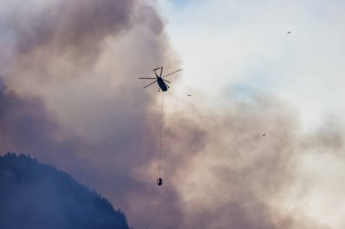 Sıcak bir yaz günü, Hope yakınlarındaki dağda, BC Orman Yangını ve Dumanı 'nın üzerinde uçan Wildfire Servis Helikopteri. British Columbia, Kanada. Doğal Felaket